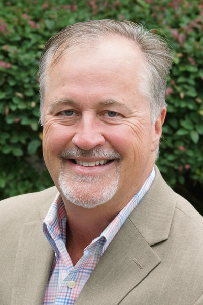 a man wearing a suit and tie smiling at the camera