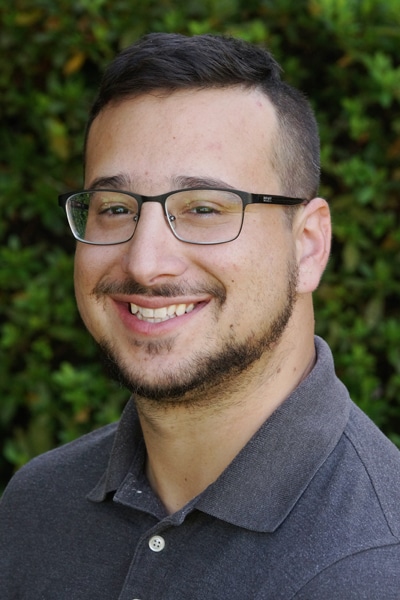 a man wearing glasses and smiling at the camera