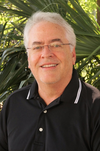 a man wearing glasses and smiling at the camera