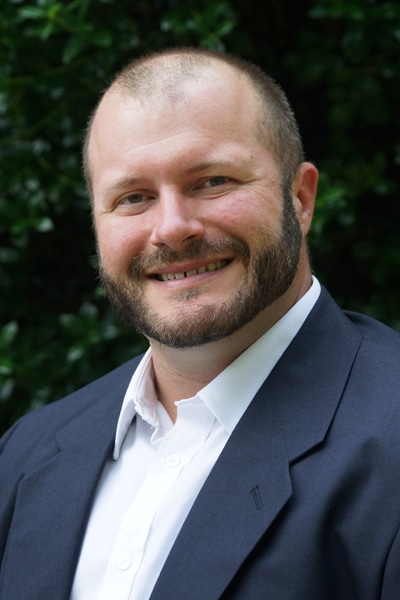 a man wearing a suit and tie smiling at the camera