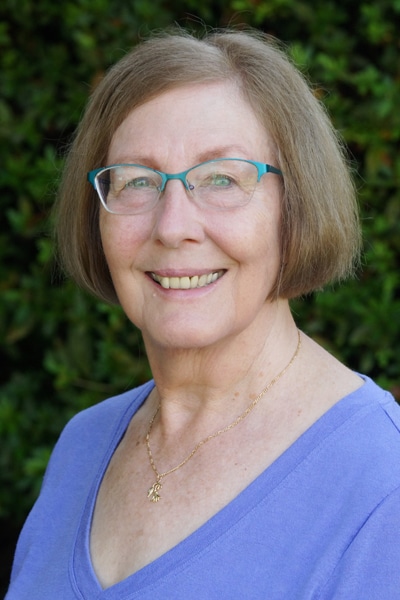 a woman wearing glasses and smiling at the camera