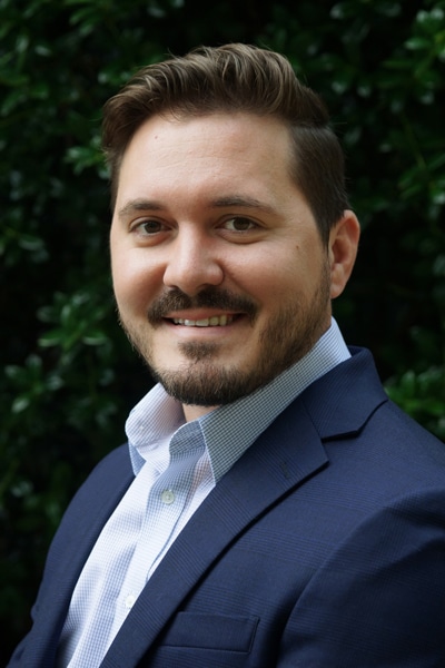 a man wearing a suit and tie smiling at the camera