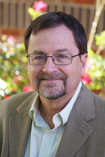 a man wearing glasses and smiling at the camera