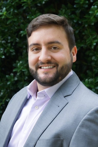 a man wearing a suit and tie smiling at the camera