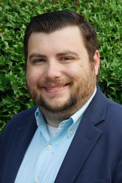 a man wearing a suit and tie smiling at the camera