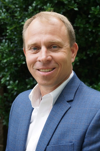 a man wearing a suit and tie smiling at the camera