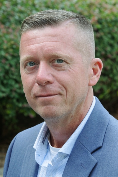 a man wearing a suit and tie smiling and looking at the camera