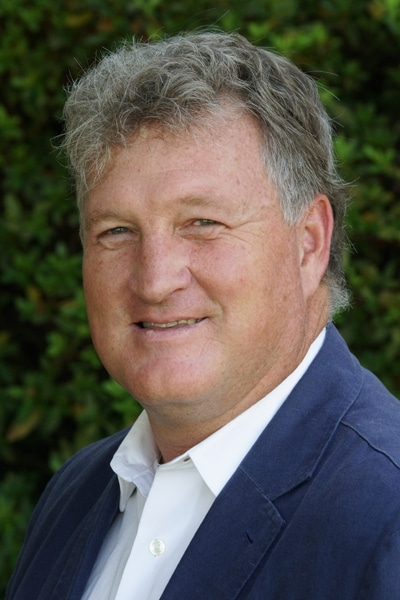 a man wearing a suit and tie smiling and looking at the camera