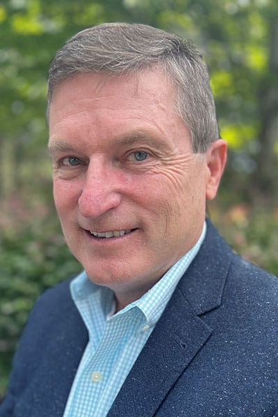 a man wearing a suit and tie smiling at the camera
