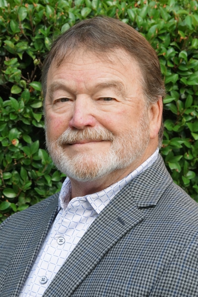 a man wearing a suit and tie smiling at the camera