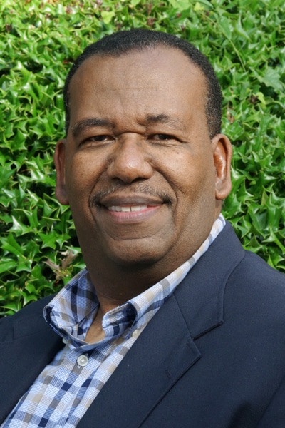 a man wearing a suit and tie smiling at the camera