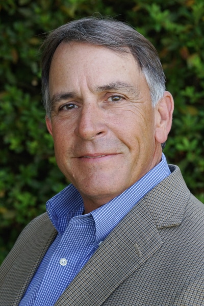 a man wearing a suit and tie smiling at the camera