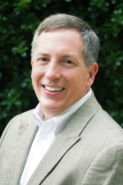 a man wearing a suit and tie smiling at the camera