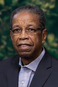 a man wearing a suit and tie smiling and looking at the camera