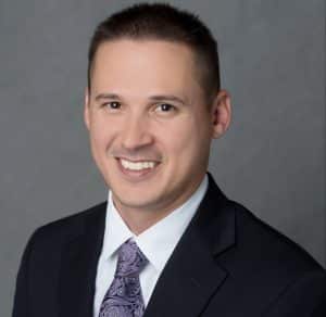 a man wearing a suit and tie smiling at the camera