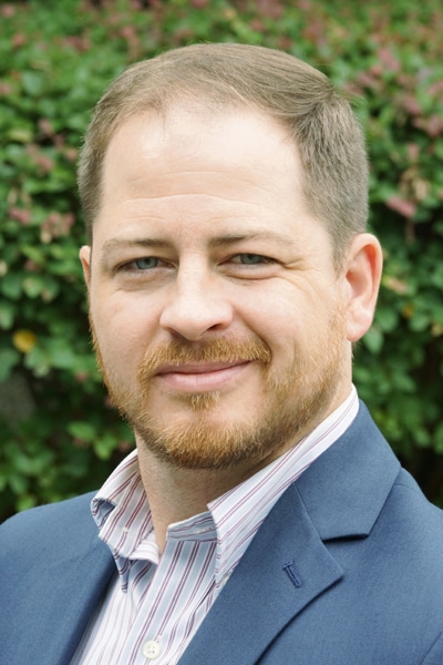 a man wearing a suit and tie smiling at the camera