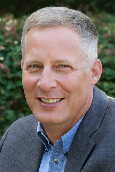 a man wearing a suit and tie smiling at the camera