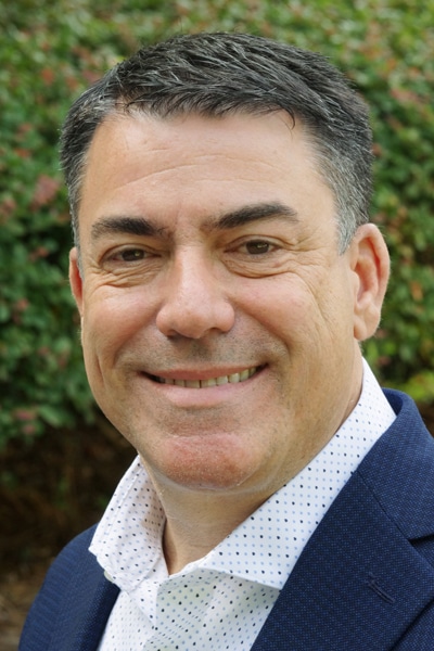 a man wearing a suit and tie smiling at the camera