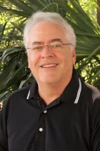 a man wearing glasses and smiling at the camera