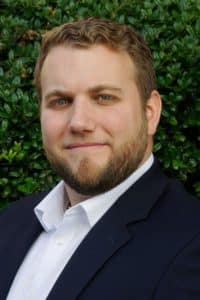 a man wearing a suit and tie smiling at the camera