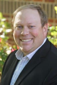 a man wearing a suit and tie smiling at the camera