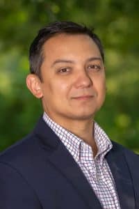 a man wearing a suit and tie smiling at the camera