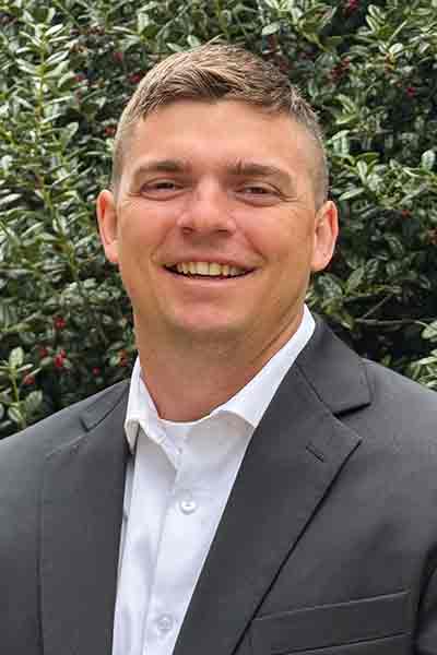 a man wearing a suit and tie smiling at the camera