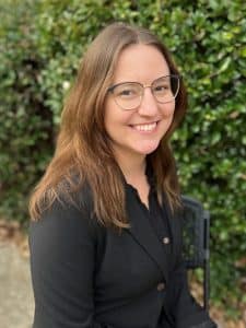 a woman wearing glasses and smiling at the camera