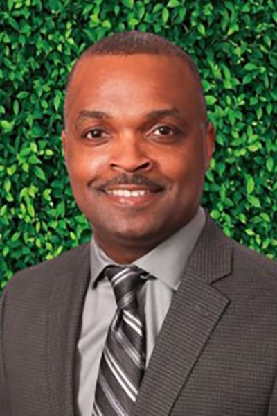 a man wearing a suit and tie smiling at the camera